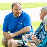 Student affairs staff member talking to man and woman in lawn chairs